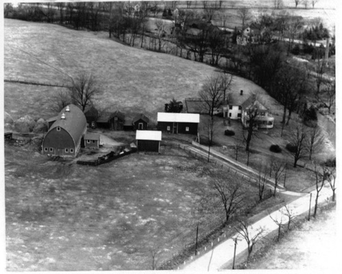 Aerial view of the Durland Farm with Lawrence house in background behind trees.
Cream Cheese factory ruins and chimney to right of Lawrence house.  Storage barn across Goshen Road. Circa 1950 chs-003314